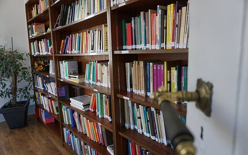 Bücherregal mit Fachliteratur, im Vordergrund eine geöffnete Tür mit Messingklinke