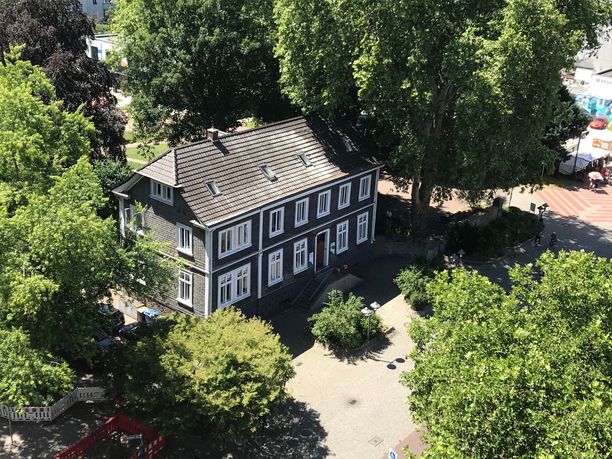 Das ifs-Haus im Sommer, umgeben von grünen Laubbäumen